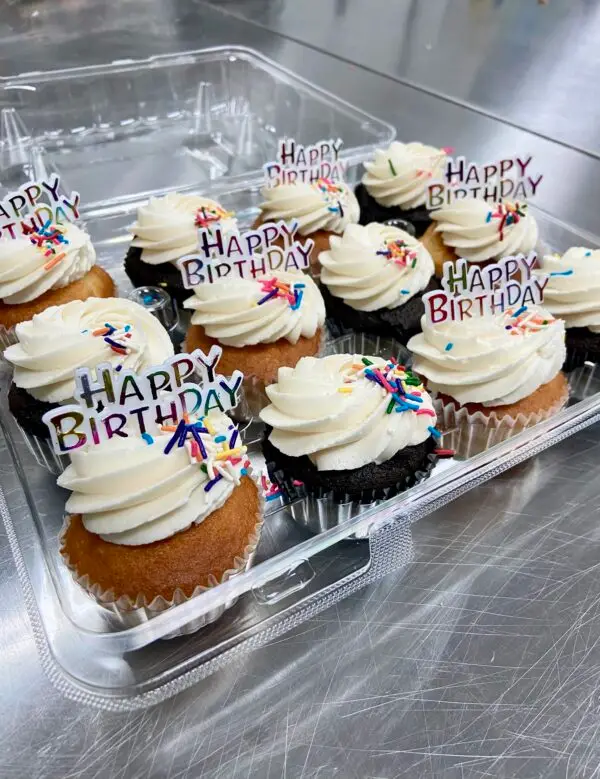 A dozen mix of chocolate and vanilla cupcakes with vanilla icing and sprinkles. Garnished with (6) Happy Birthday Toppers