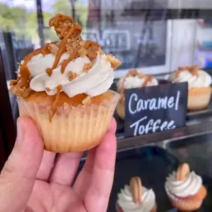 Vanilla cupcake with vanilla icing and a toffee garnish and caramel drizzle