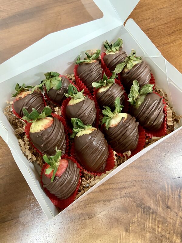 A dozen chocolate covered strawberries in a standard box